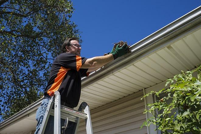 a handyman adjusting a gutter to direct rainwater away from a building in Bedford Park, IL